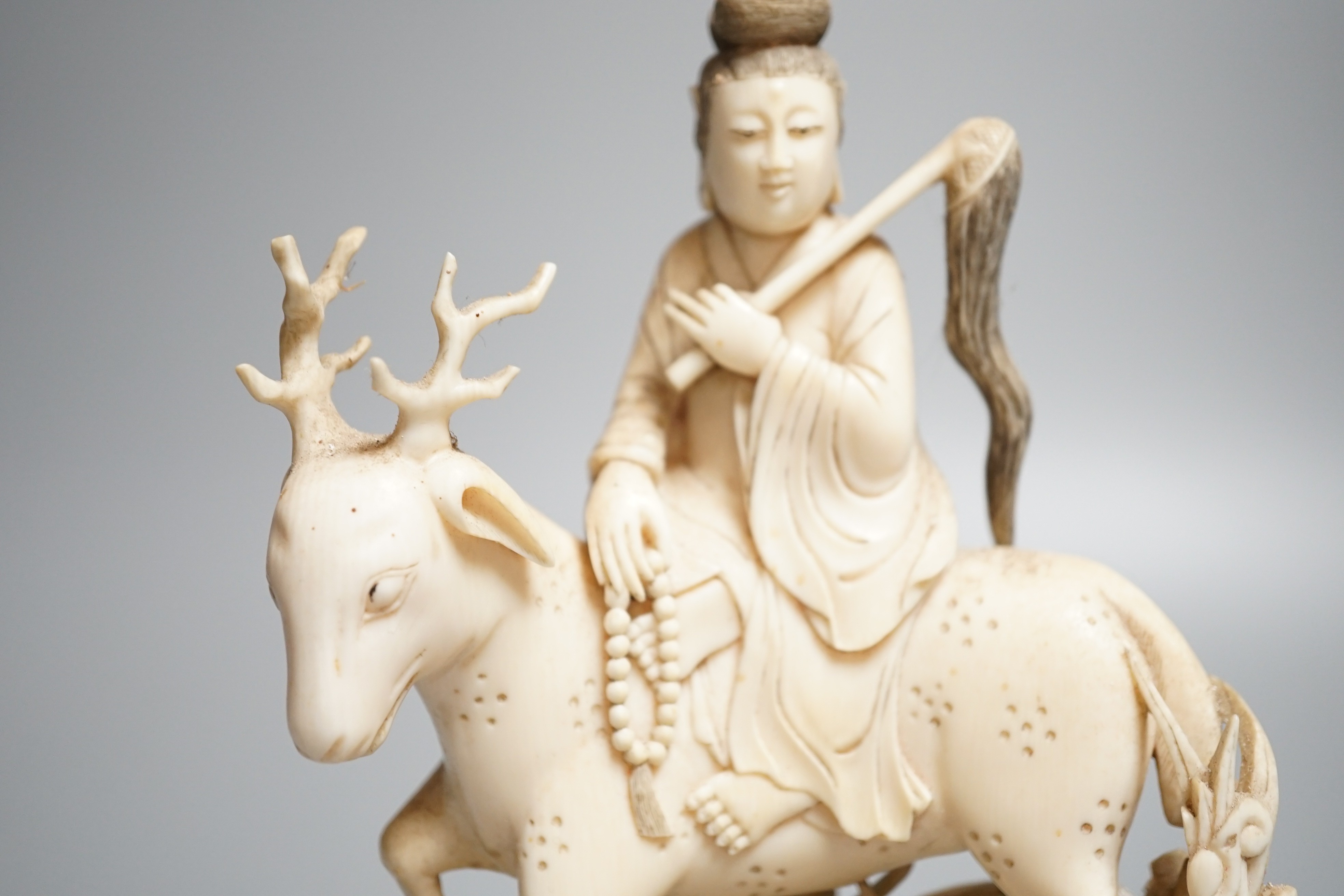 A Chinese carved ivory figure of a female immortal riding a deer, early 20th century, height 17cm excl. stand